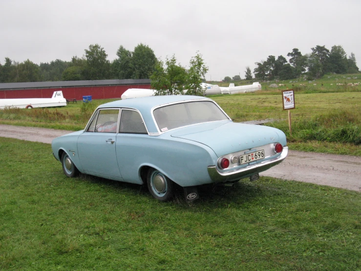 the old car is parked in front of the barn