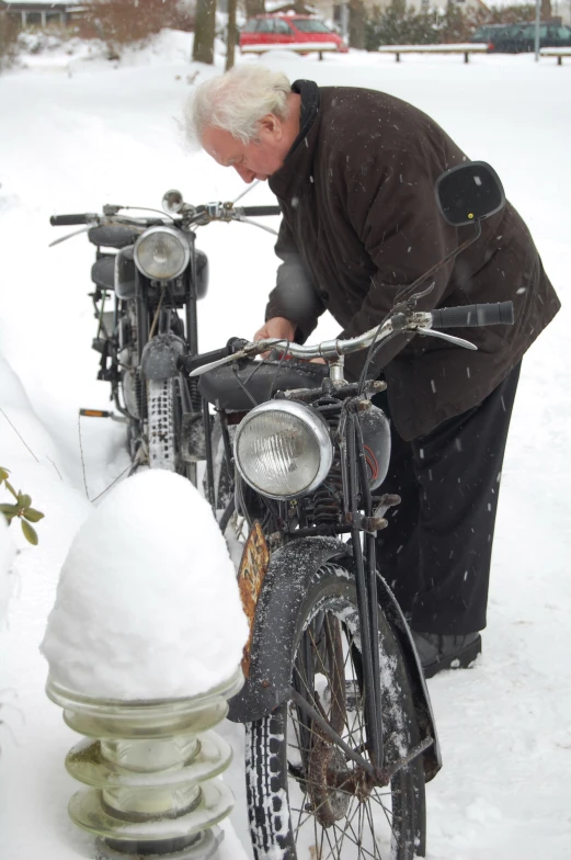 a man fixing his bike with snow piled behind it