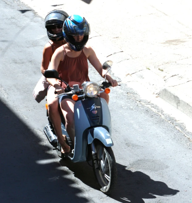 two people on a motor scooter ride down the street