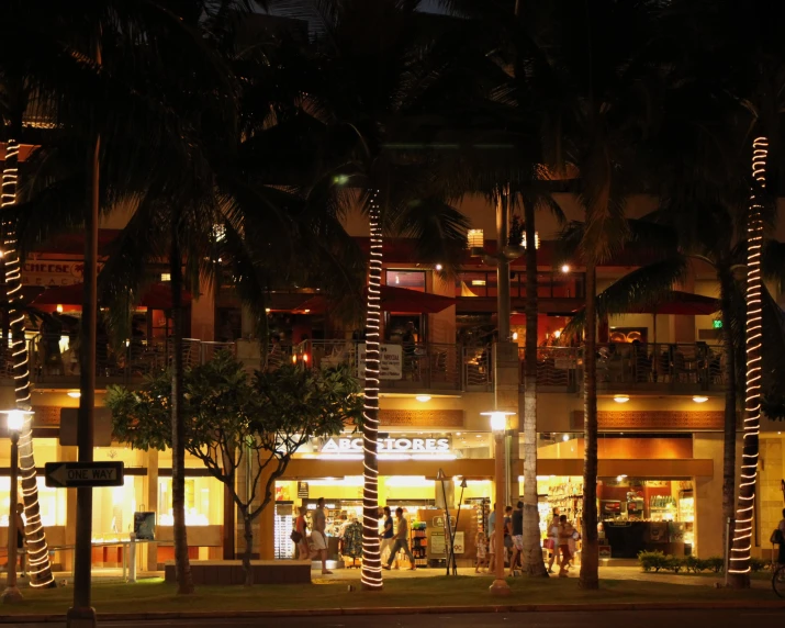 people standing on the sidewalk at night in front of the store