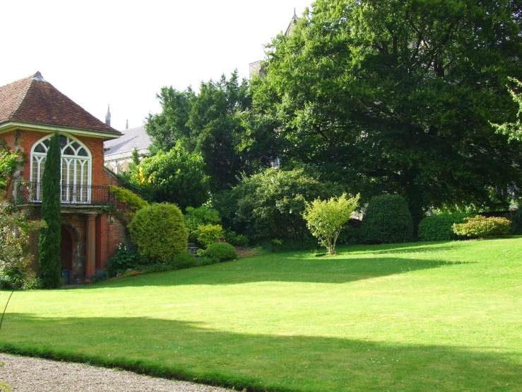 large lawn next to brick building with lots of green bushes
