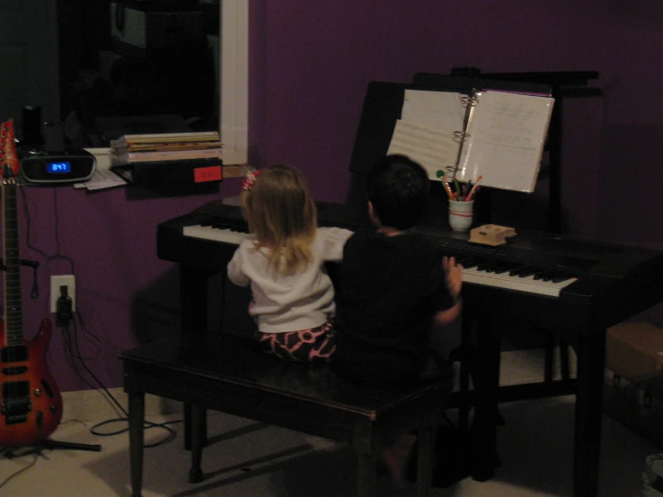 two s playing an electric keyboard in a purple room