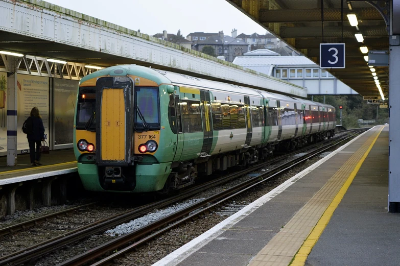 a commuter train stops at the station at dusk