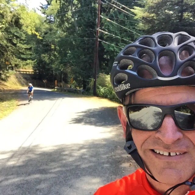 a man that is wearing sunglasses and riding a bike