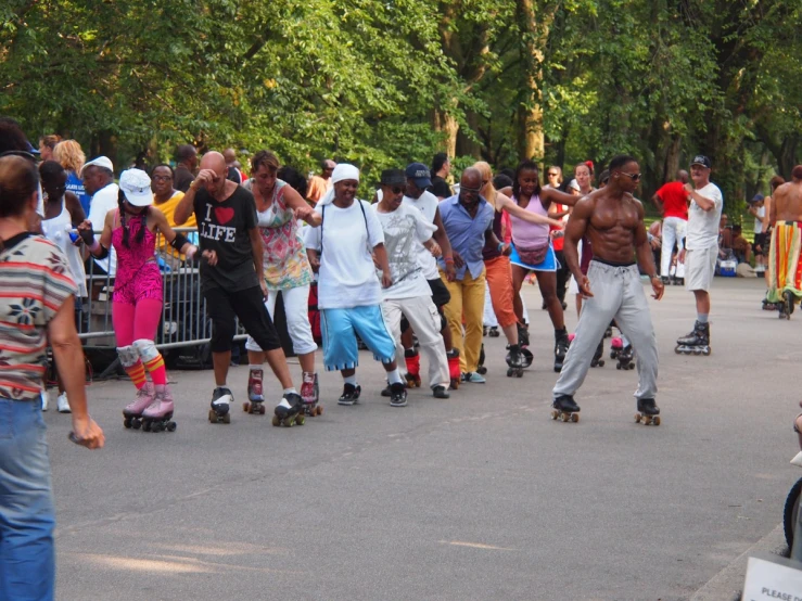 many men and women are riding skateboards on the road