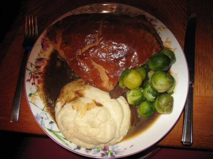 a plate with mashed potatoes, brussel sprouts, and meat