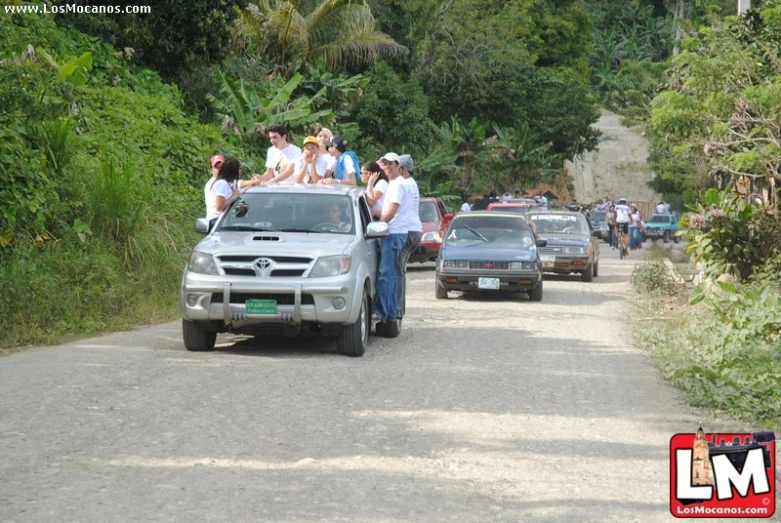 the people stand in between a pick up truck and a row of cars