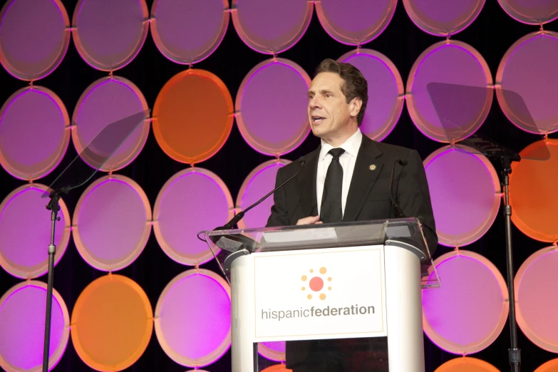 a man wearing a suit and tie giving a speech at an award event