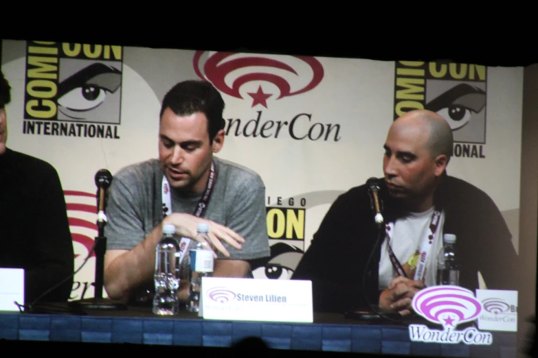 a couple of men sitting next to each other at a table