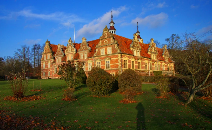 large brown building with ornate spires next to a tree