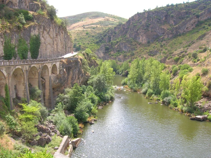 an old train traveling over a bridge on the side of a river