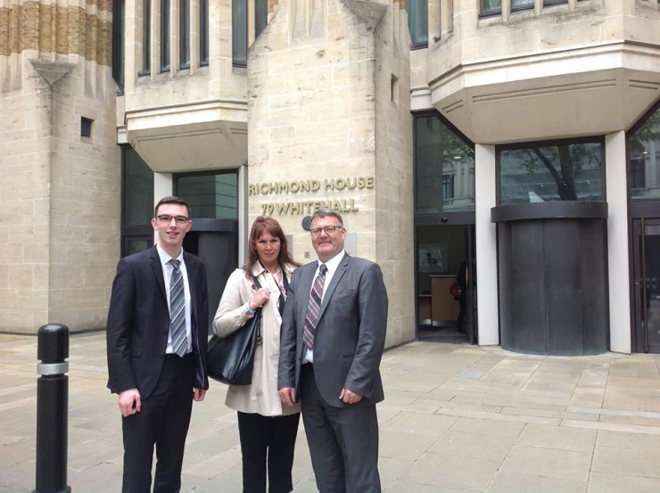 three people standing outside of a large building