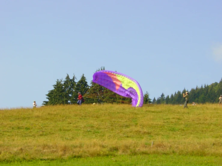 two people on a grassy hill flying a kite