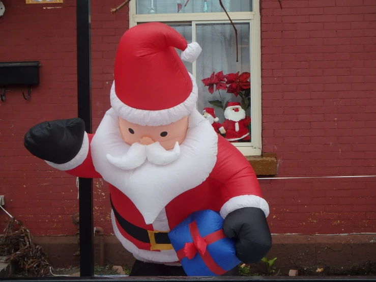 large inflatable santa clause standing outside near red brick house