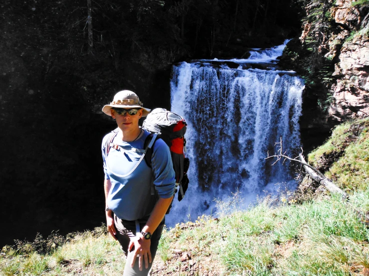 a person walking up the side of a mountain near a waterfall