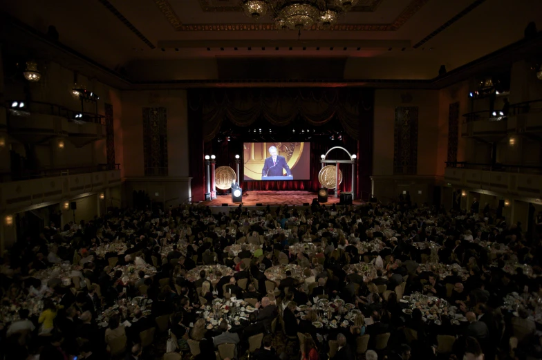 an audience in a large hall with a screen