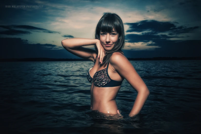 a woman in a black bikini is posing in the water