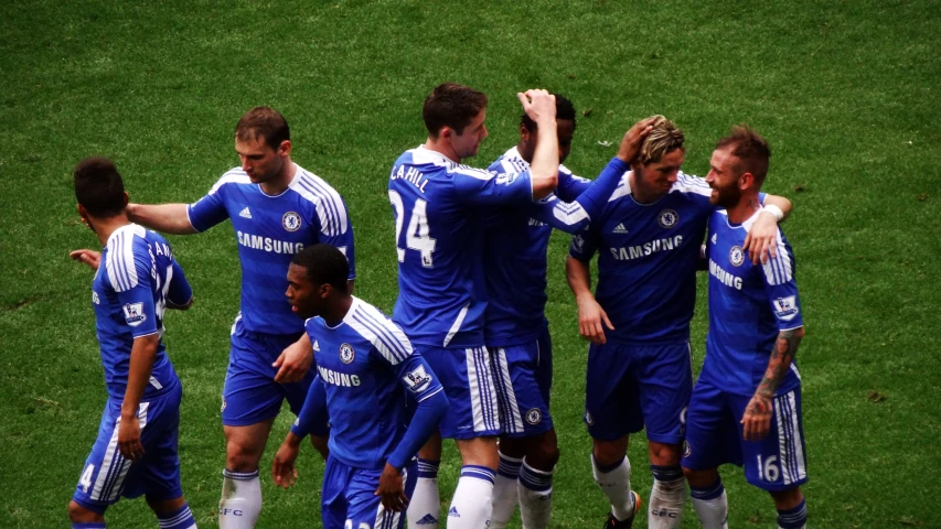 a group of soccer players huddle together on the field