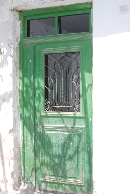 green metal door next to white building with black windows