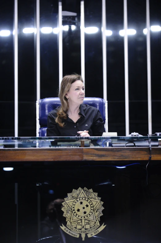 a woman sitting at a desk with a light on behind her