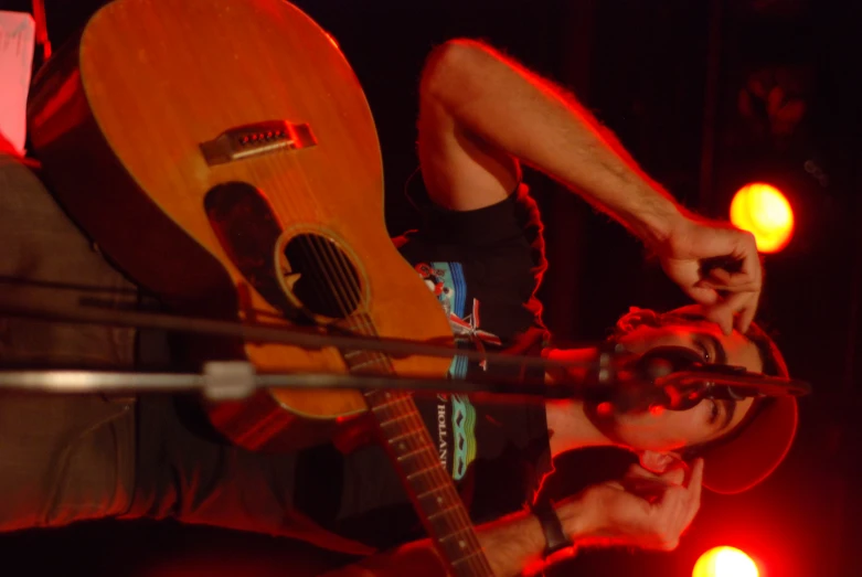 a man with a hat holding up his guitar