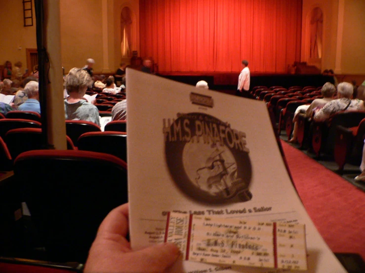a man holding a pamphlet in front of an auditorium