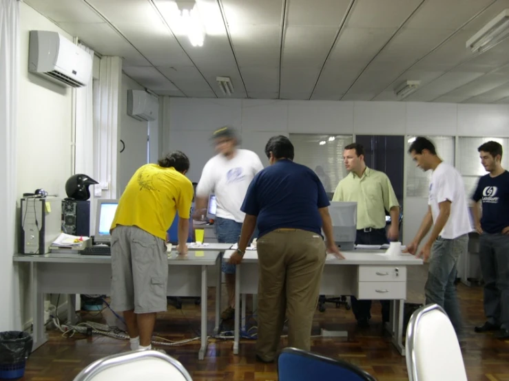 a bunch of men standing around a desk