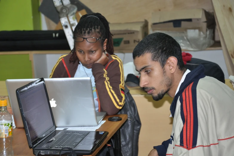 two people sitting at a table using laptops