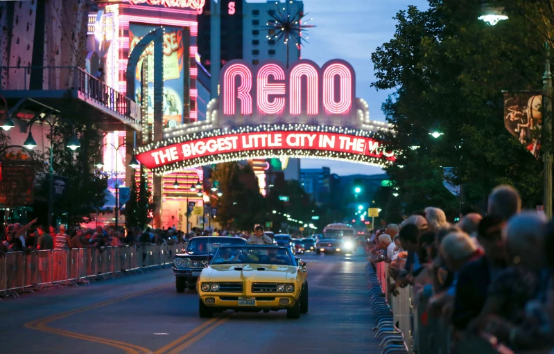 a taxi rides under neon signs in front of an entrance into a city