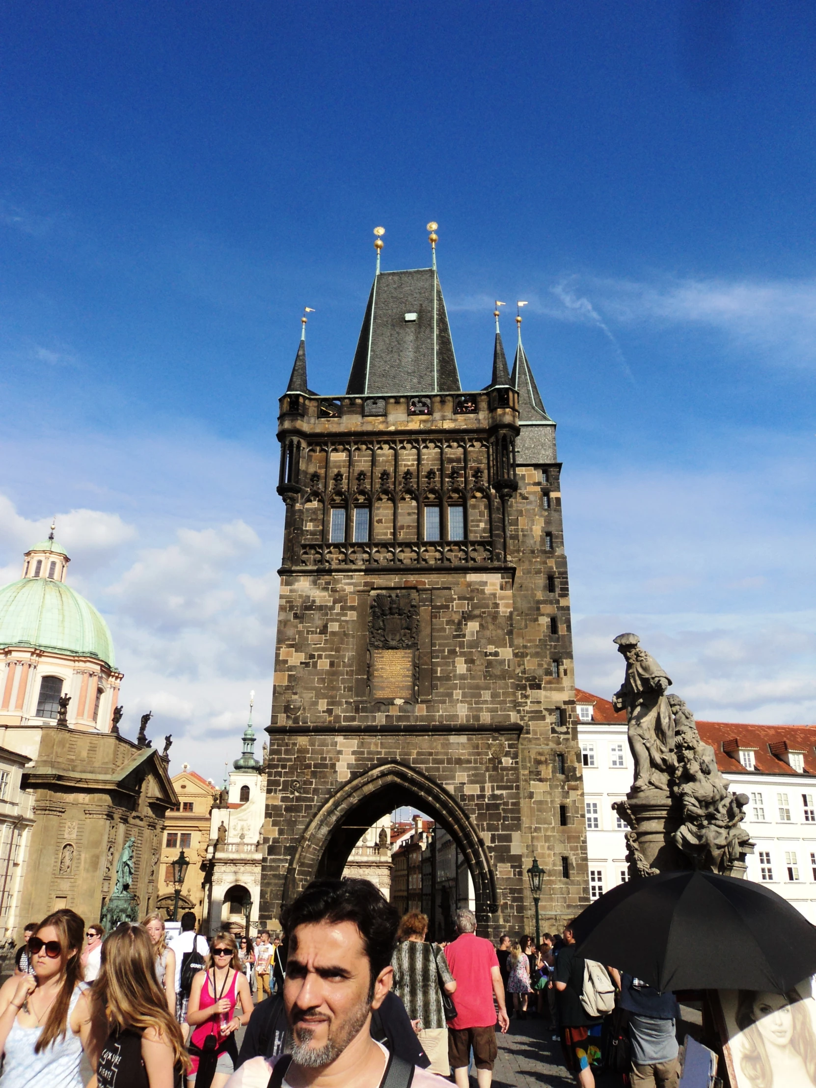 people walk near an ancient clock tower on a clear day