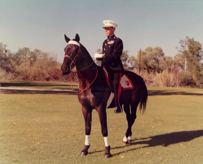 the man in uniform sits atop of his horse