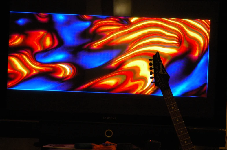 a guitar is positioned in front of an illuminated wall
