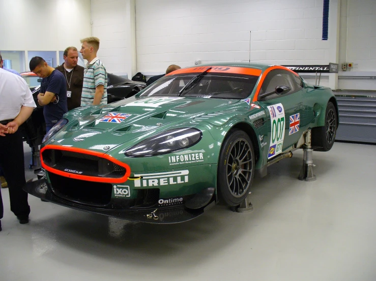 green sports car in racing pit with other cars