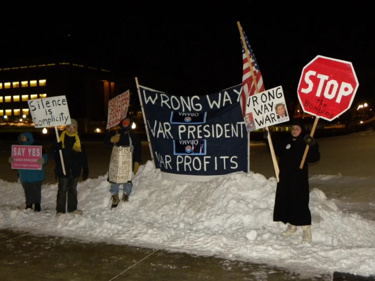 several people holding signs with their faces down at night