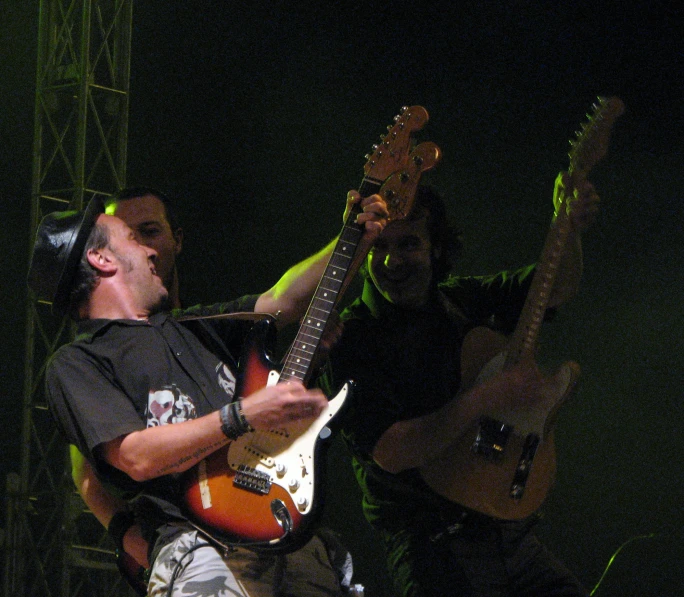 two guitarists on stage with one of them holding a guitar