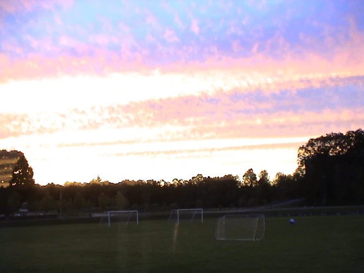 a sunset with many soccer goal posts out front