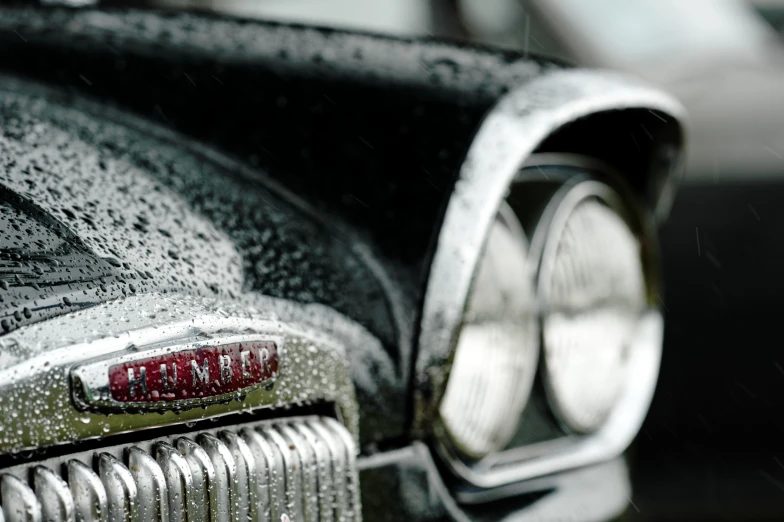 close up of car's bumper grill and front lights with raindrops