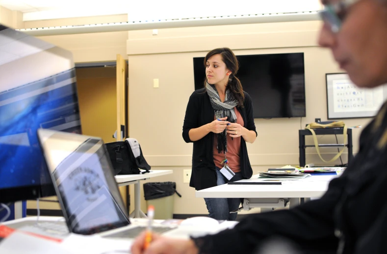 a woman standing next to another person using a computer