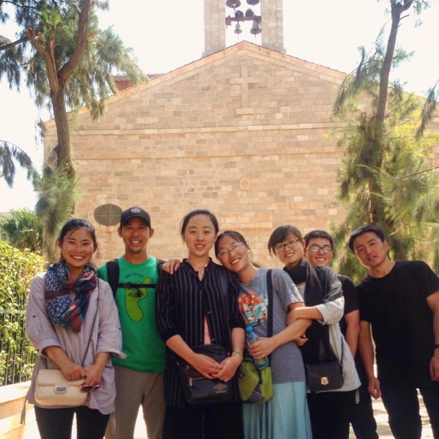 a group of students standing outside of a building with trees