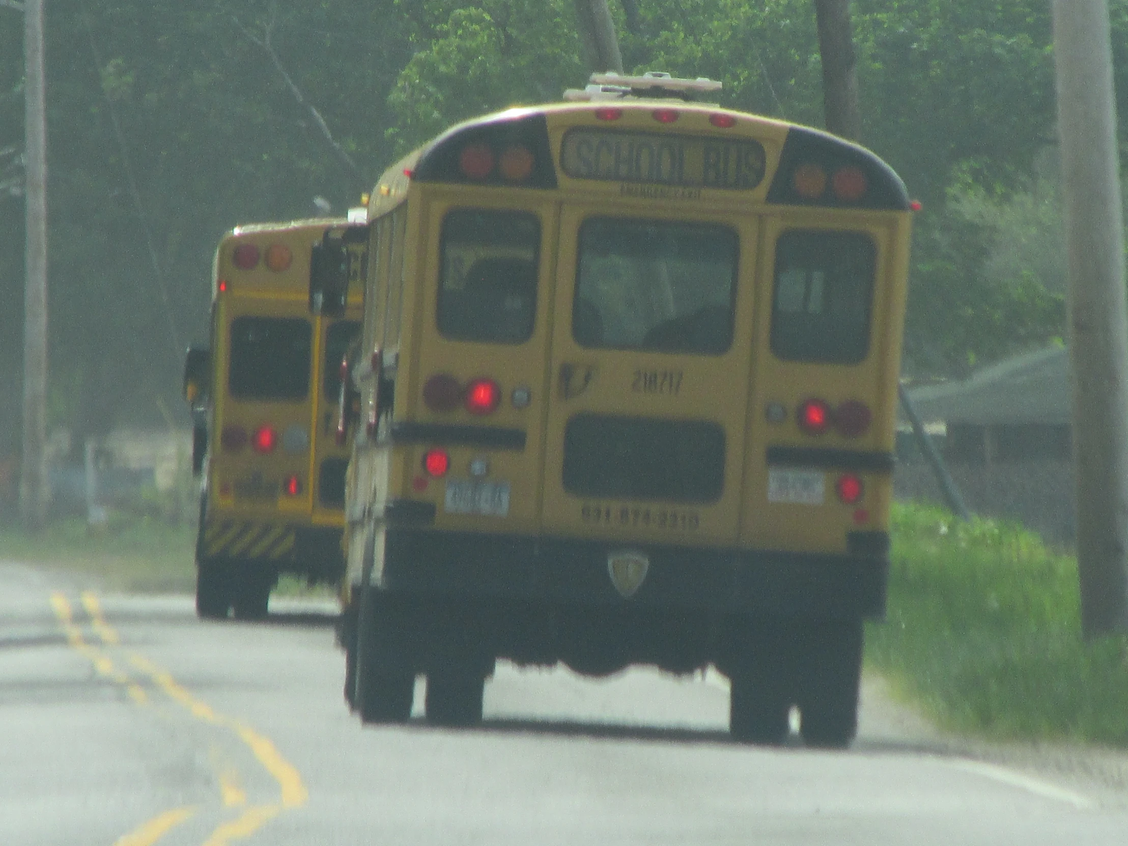 the three yellow school buses are driving down the road