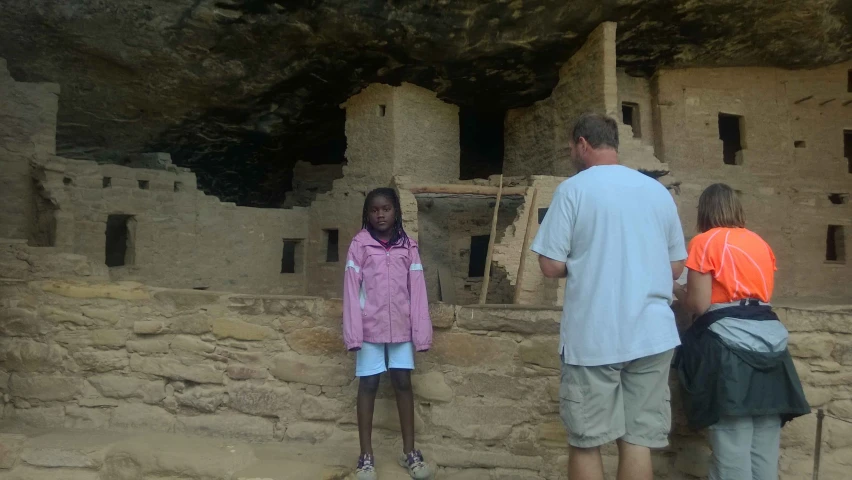 a man and two s on a hike standing in front of an ancient building