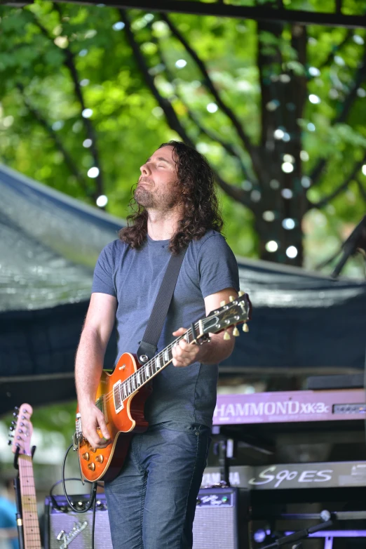 a man standing on a stage with his mouth open and playing an orange guitar