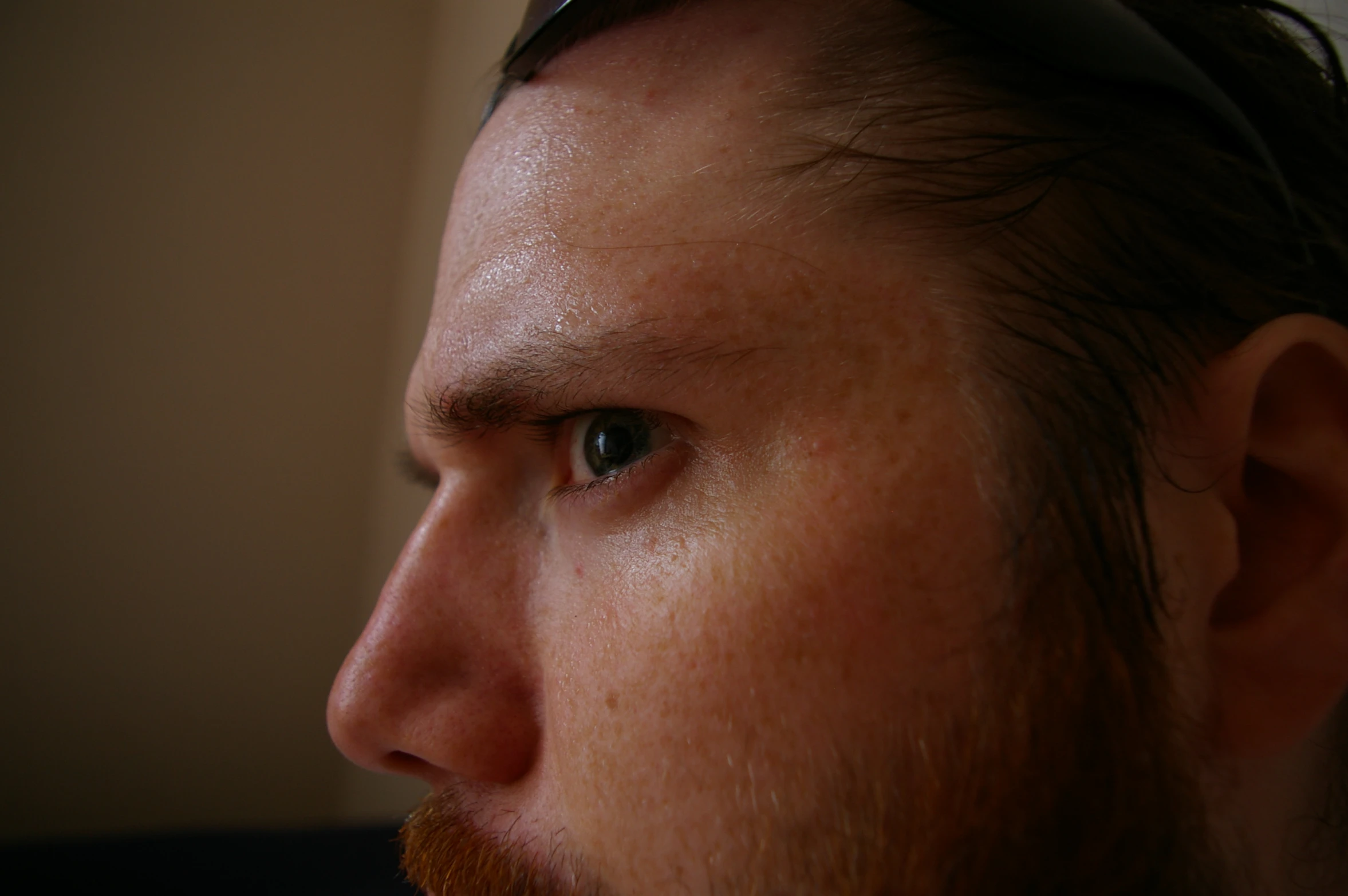 a man's face, with his hair in the foreground and a brown beard