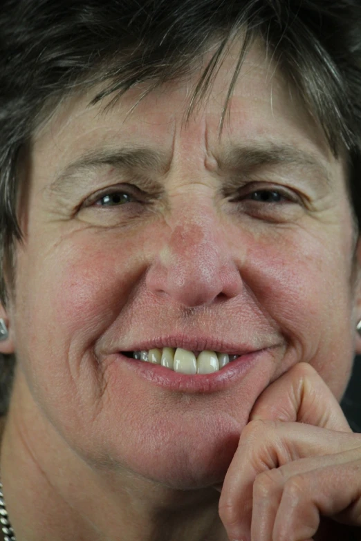 a woman smiling for the camera, in front of a black background