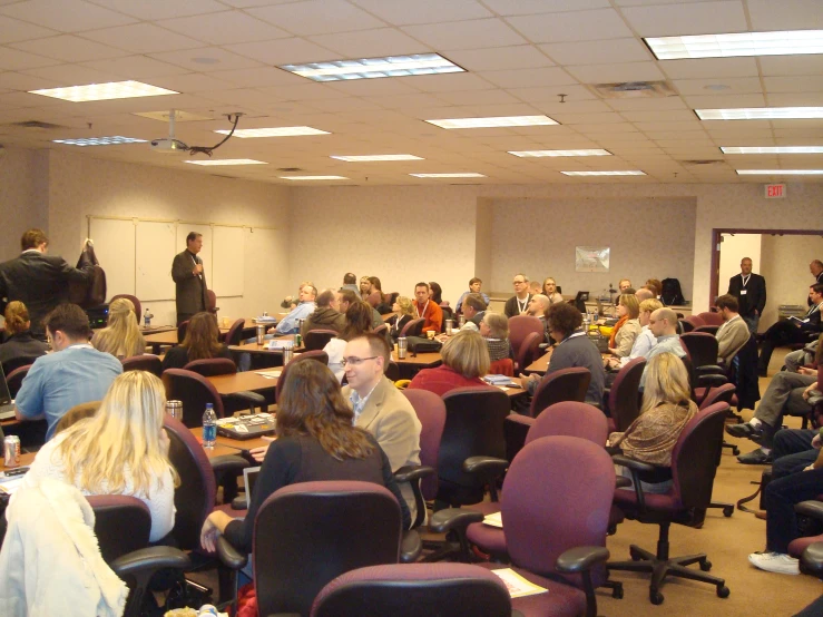 group of people sitting down in chairs and taking notes