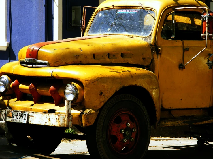 a yellow vintage truck parked next to a blue house