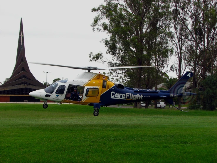 a blue, yellow and white helicopter is parked in the grass