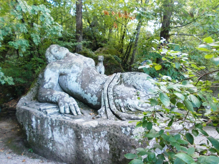 a statue is laying on its side next to bushes