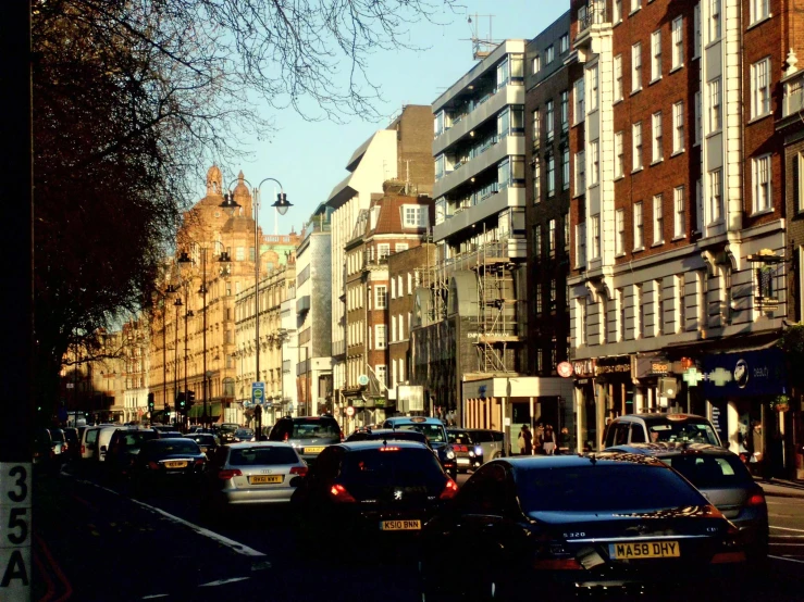 a city street with parked cars and tall buildings on either side