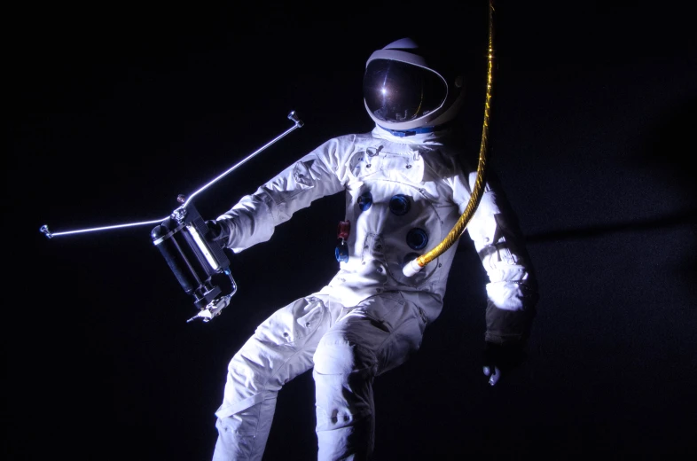 an astronaut dressed in a white space suit holding a rope